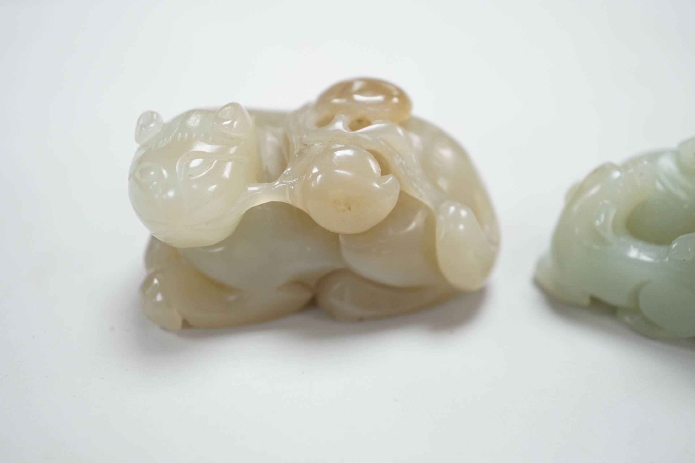 A Chinese celadon and brown jade figure of a cat biting a peach branch and a celadon jade group of a dog and puppy, cat biting a peach branch 5cm wide (2)